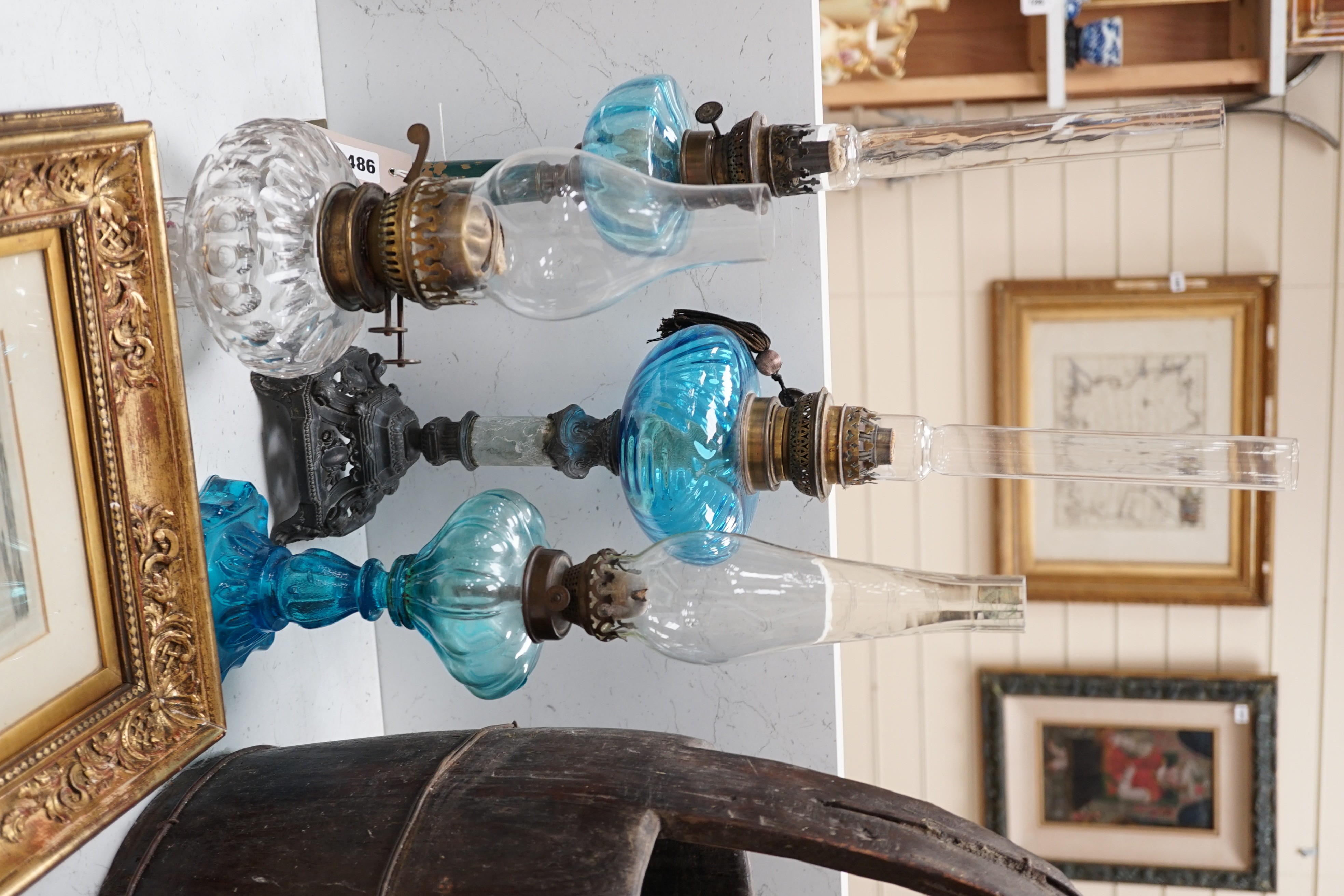 Three blue glass oil lamps and a clear glass oil lamp, tallest 62cms high